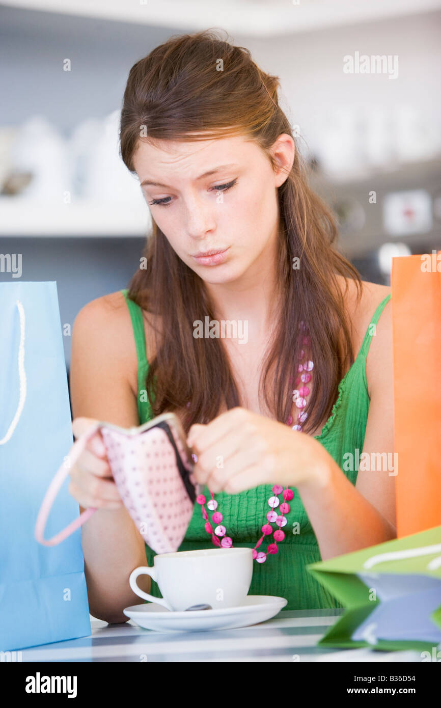 Giovane donna seduta al tavolo controllo portamonete Foto Stock
