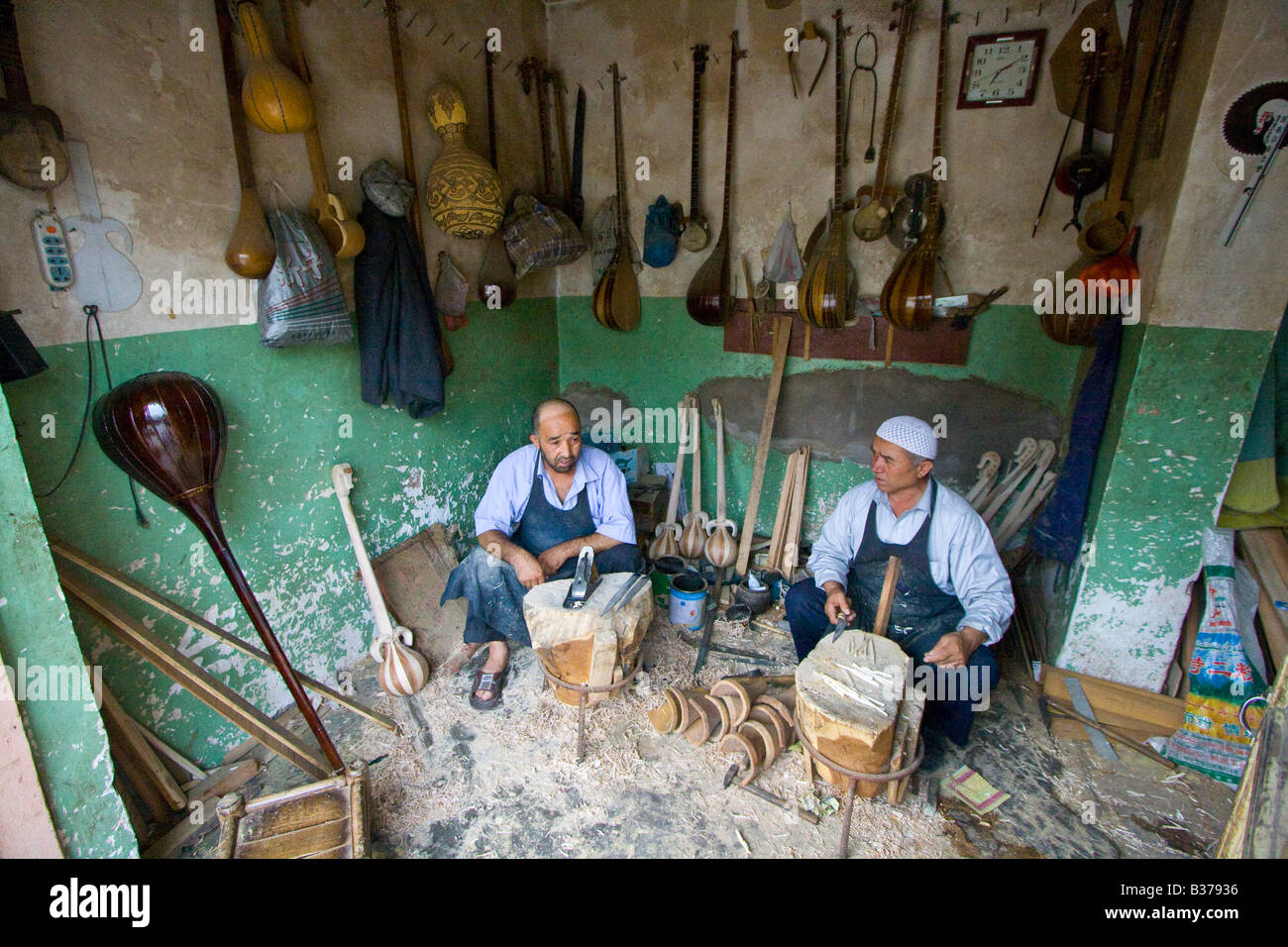 Uyghur gli artigiani produrre legno tradizionali strumenti musicali a Kashgar nella provincia dello Xinjiang Cina Foto Stock