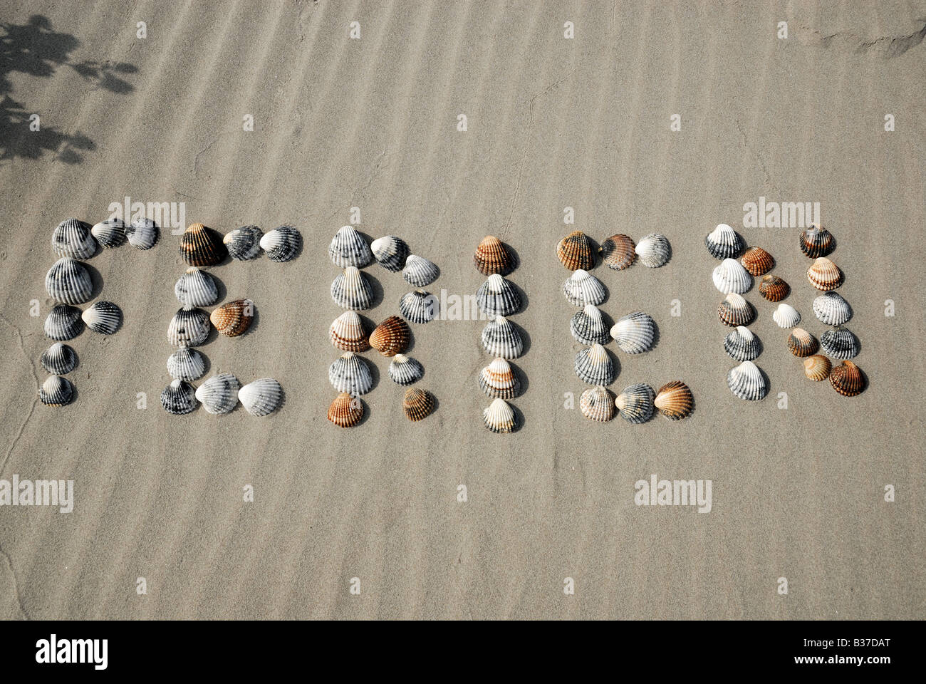 La parola Ferien - Tedesco per vacanza, fatta di conchiglie sulla spiaggia Foto Stock