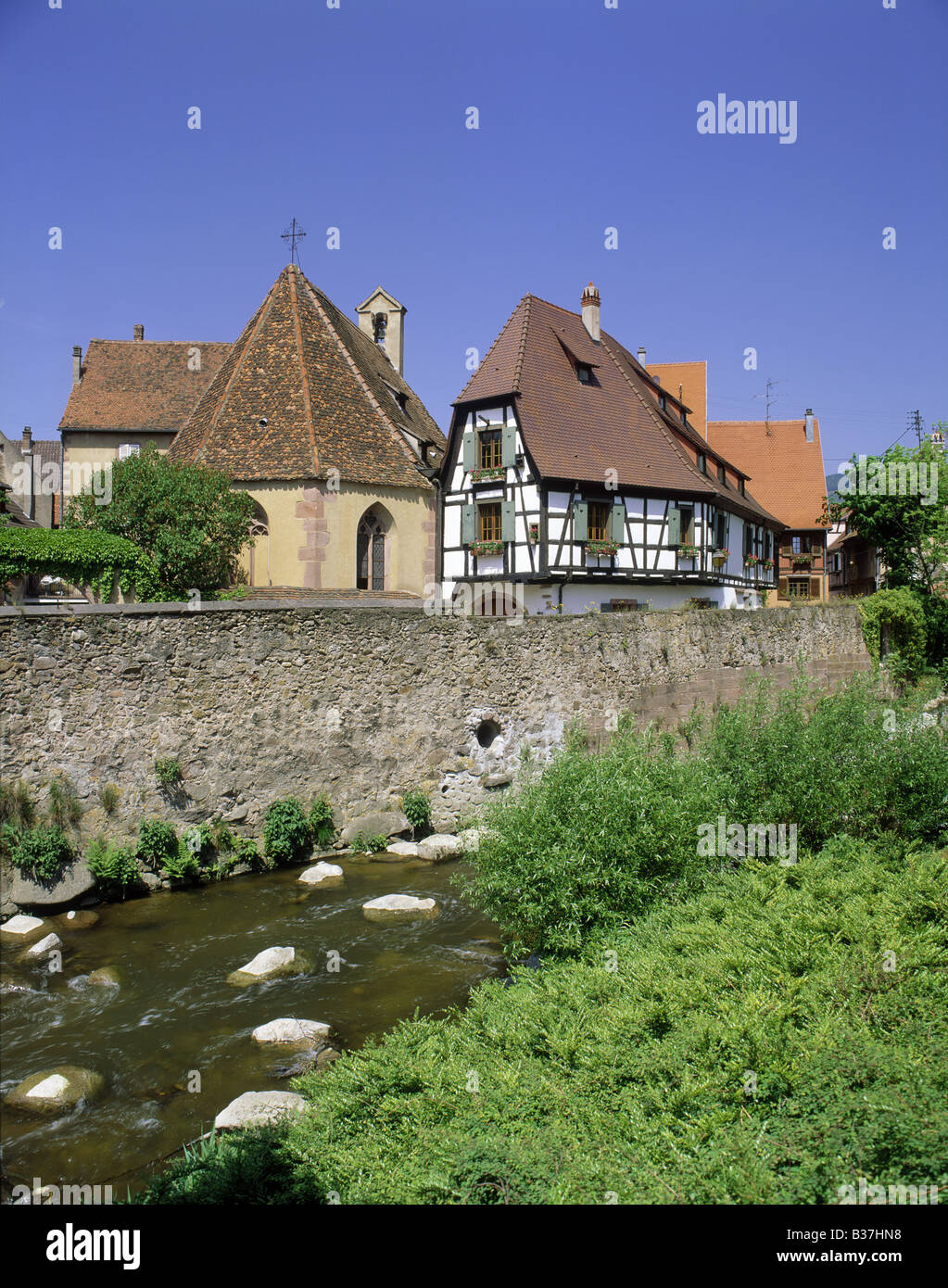 Graticcio casa fiori in scatole di finestra persiane cappella di pietra di fiume Weiss KAYSERSBERG ALSACE FRANCIA Foto Stock