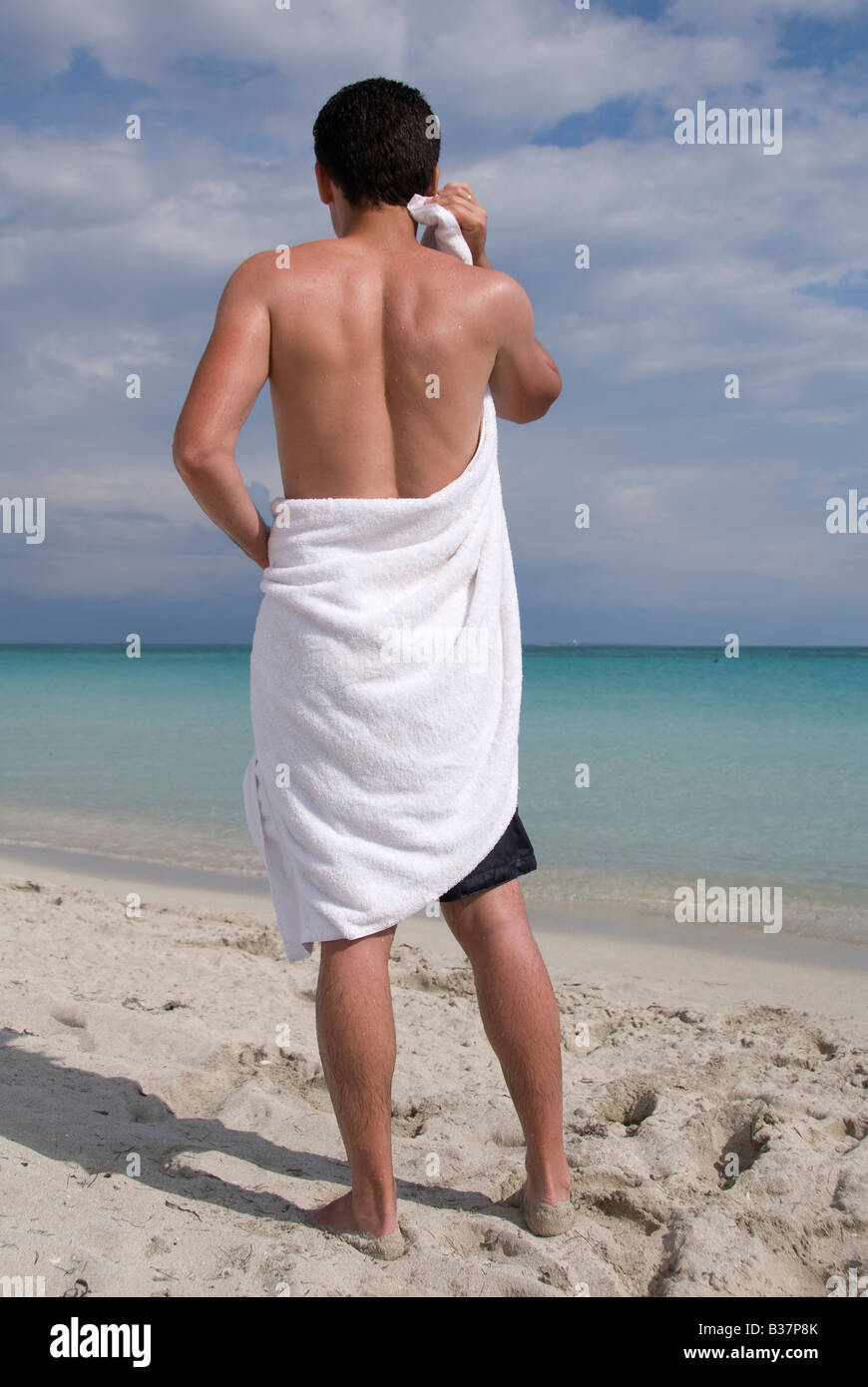 Un uomo onself asciugatura con un asciugamano su una spiaggia Foto Stock