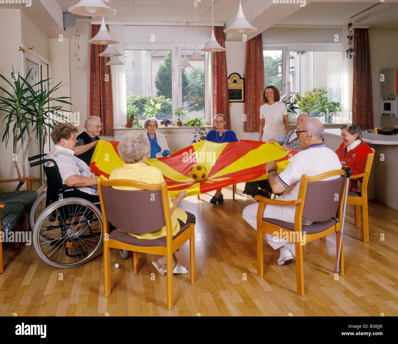 Gruppo di anziani a giocare con la palla ed un foglio di tela abrasiva casa di riposo in Germania Foto Stock