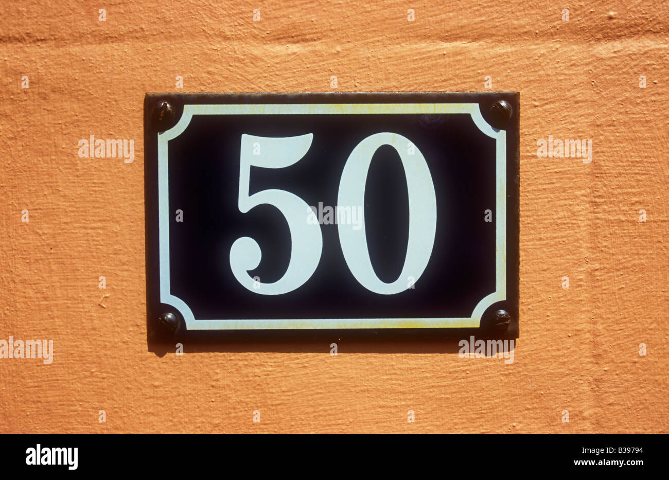 Close up di colazione continentale in stile Europeo di blu e smalto bianco numero di casa segno indicante 50 sul salmone-parete rosa Foto Stock