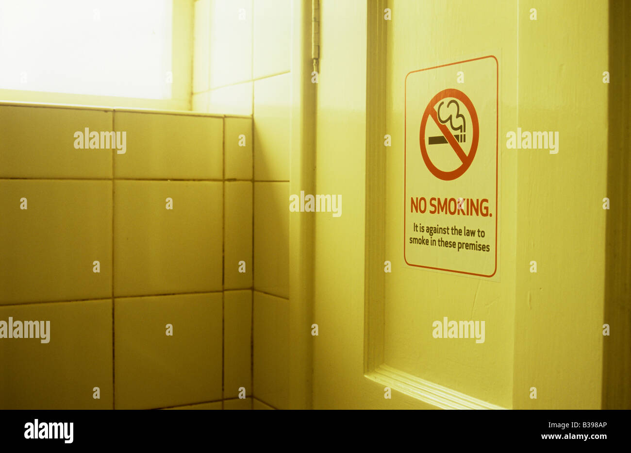 Cartello sulla porta di legno in mattonelle bianche in camera calda luce dicendo con icona fumare non è contro la legge di fumare in questi locali Foto Stock