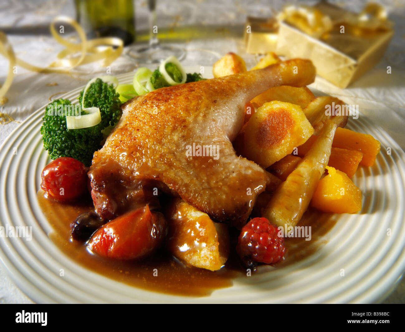 Gamba d'anatra arrosto Gresham servita con salsa di frutta invernale, patate arrosto e verdure in un ambiente festoso Foto Stock