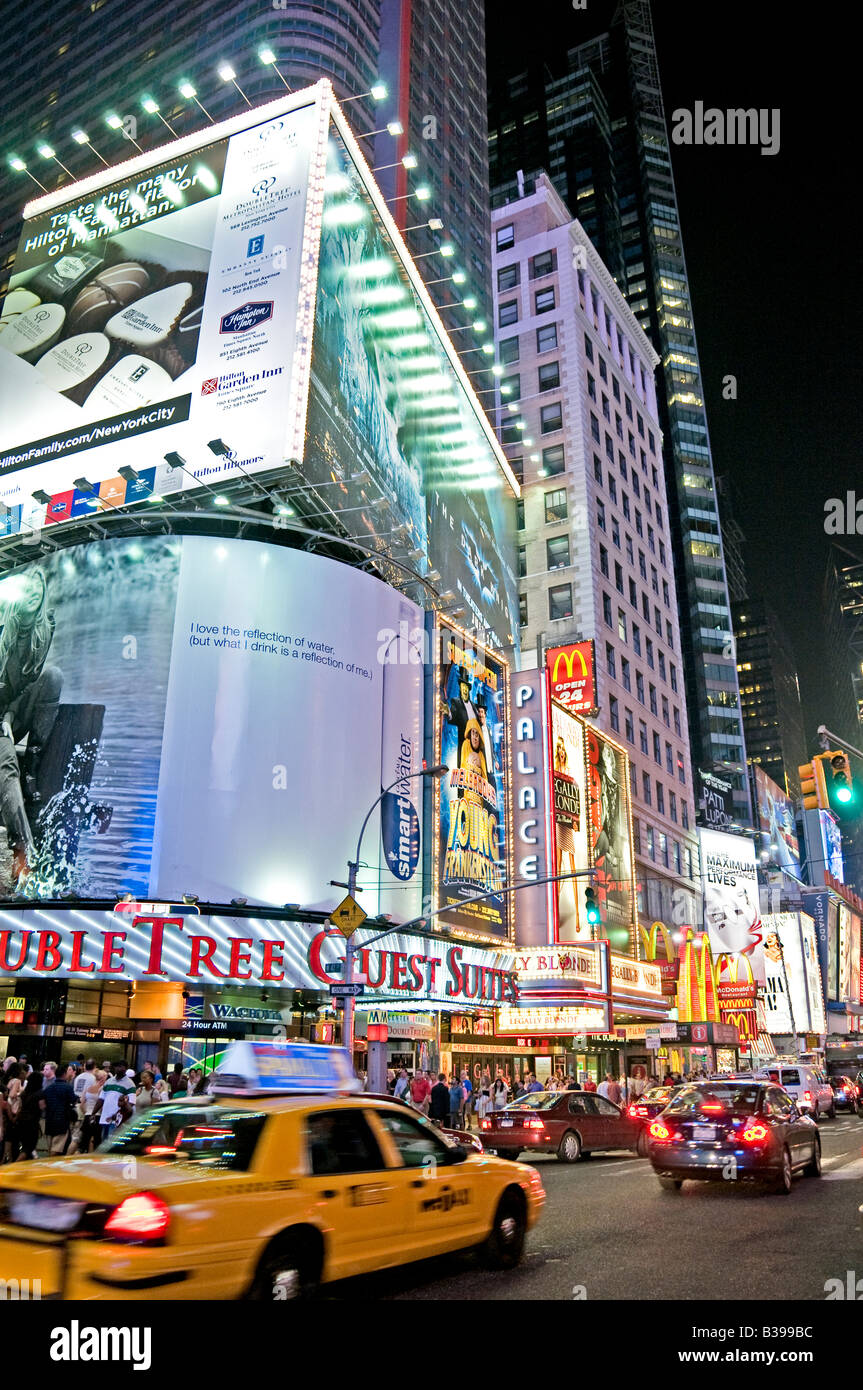 Times Square Night Scene New York City // NEW YORK CITY, New York: Una vivace scena notturna di Times Square, l'iconico incrocio di Midtown Manhattan, brulica di attività. I taxi gialli navigano attraverso le strade affollate, il loro colore distintivo si distingue sullo sfondo di luminosi cartelli al neon, enormi cartelloni e schermi LED. Un gran numero di pedoni, sia turisti che locali, riempiono i marciapiedi e i marciapiedi, incarnando l'energia della "città che non dorme mai". Foto Stock