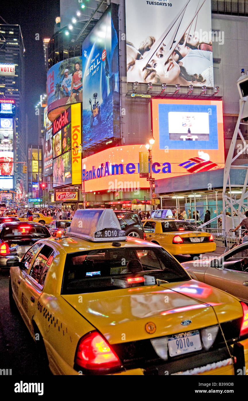 Times Square Yellow Taxis Night New York City // NEW YORK CITY, New York - Una vivace scena notturna di Times Square, l'iconico incrocio di Midtown Manhattan, brulica di attività. I taxi gialli navigano attraverso le strade affollate, il loro colore distintivo si distingue sullo sfondo di luminosi cartelli al neon, enormi cartelloni e schermi LED. Un gran numero di pedoni, sia turisti che locali, riempiono i marciapiedi e i marciapiedi, incarnando l'energia della "città che non dorme mai". Foto Stock
