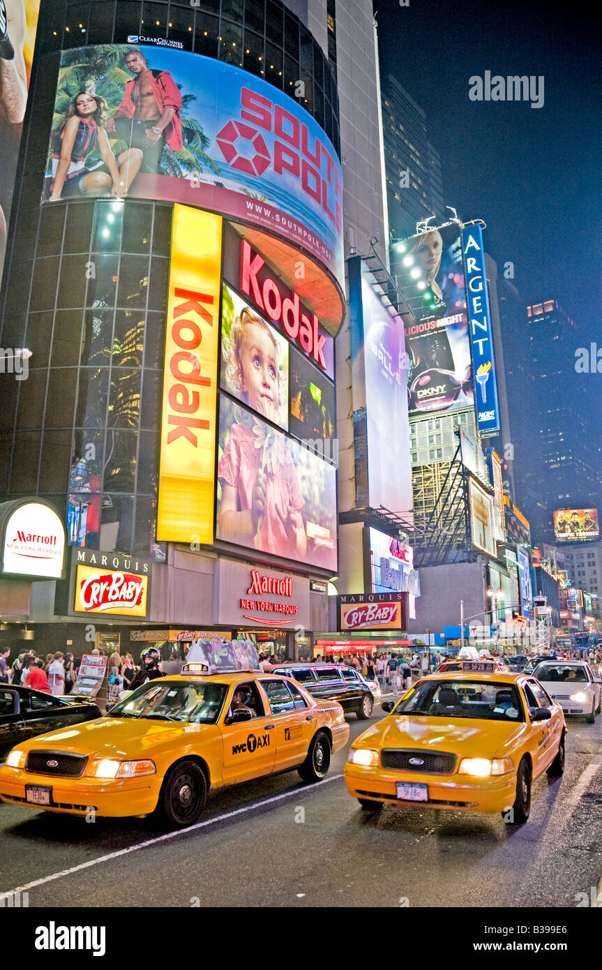 Times Square Neon Signs Yellow Taxis New York City // NEW YORK CITY, NY - Una vivace scena notturna di Times Square, l'iconico incrocio di Midtown Manhattan, brulica di attività. I taxi gialli navigano attraverso le strade affollate, il loro colore distintivo si distingue sullo sfondo di luminosi cartelli al neon, enormi cartelloni e schermi LED. Un gran numero di pedoni, sia turisti che locali, riempiono i marciapiedi e i marciapiedi, incarnando l'energia della "città che non dorme mai". Foto Stock