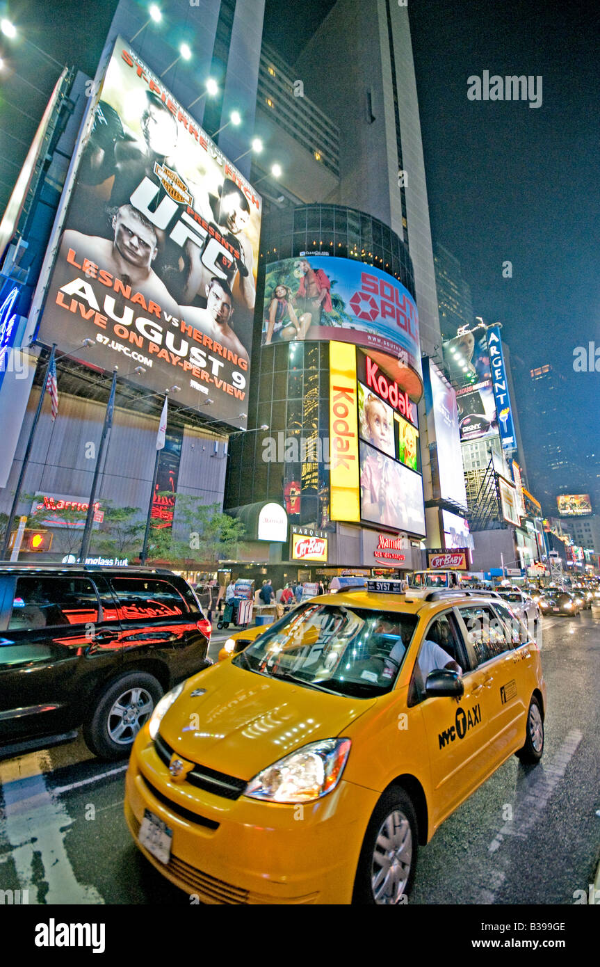 Times Square Night Scene Yellow taxi New York City // NEW YORK CITY, NY - Una vivace scena notturna di Times Square, l'iconico incrocio di Midtown Manhattan, brulica di attività. I taxi gialli navigano attraverso le strade affollate, il loro colore distintivo si distingue sullo sfondo di luminosi cartelli al neon, enormi cartelloni e schermi LED. Un gran numero di pedoni, sia turisti che locali, riempiono i marciapiedi e i marciapiedi, incarnando l'energia della "città che non dorme mai". Foto Stock