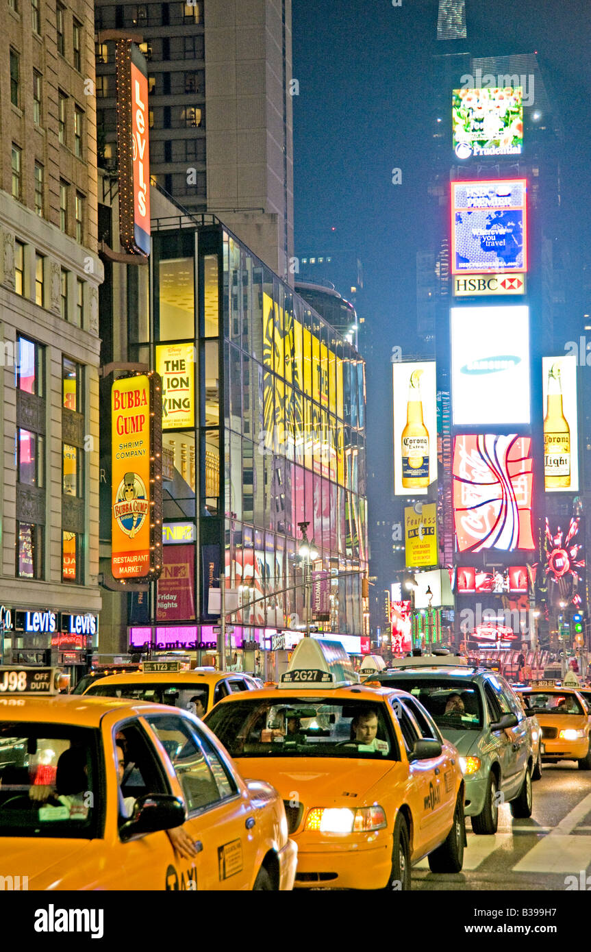 Times Square Neon Signals e Yellow Taxis New York City // NEW YORK CITY, New York - Una vivace scena notturna di Times Square, l'iconico incrocio di Midtown Manhattan, brulica di attività. I taxi gialli navigano attraverso le strade affollate, il loro colore distintivo si distingue sullo sfondo di luminosi cartelli al neon, enormi cartelloni e schermi LED. Un gran numero di pedoni, sia turisti che locali, riempiono i marciapiedi e i marciapiedi, incarnando l'energia della "città che non dorme mai". Foto Stock