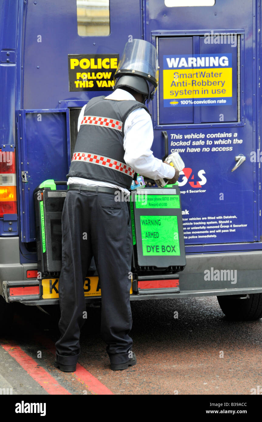 La guardia di sicurezza di manipolazione del contenitore di denaro accanto al portello di accesso posteriore del gruppo4 Securicor bullion van Foto Stock