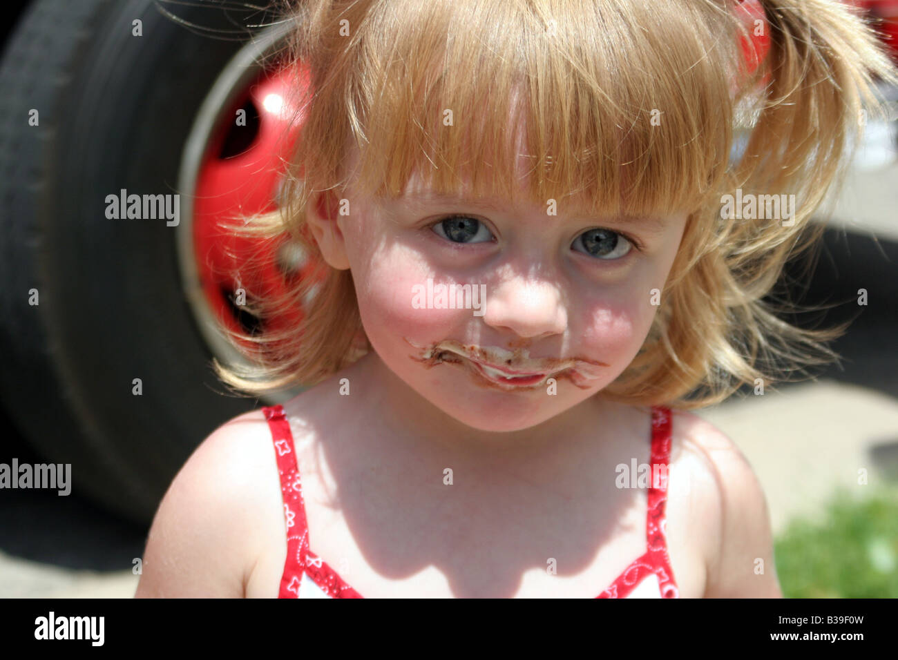 Una giovane ragazza con un confuso faccia da mangiare un gelato al cioccolato bar Foto Stock