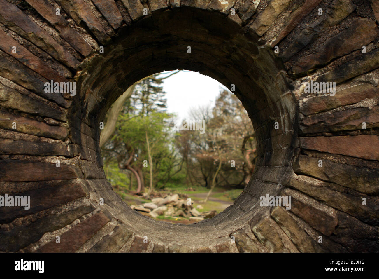Una vista attraverso un foro in una parete di un giardino Foto Stock
