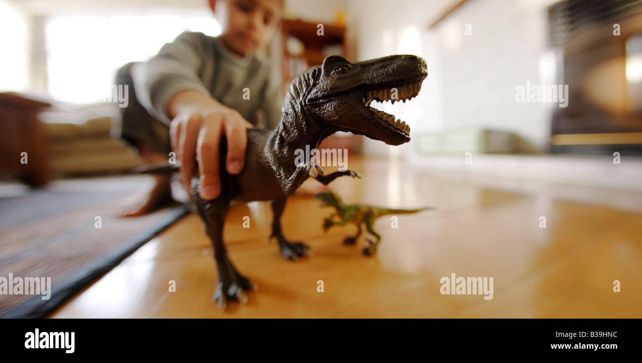 Modello Tyrannosaurus rex nelle mani di sei anni vecchio ragazzo di mangiare un altro giocattolo dinosauro un velociraptor Foto Stock