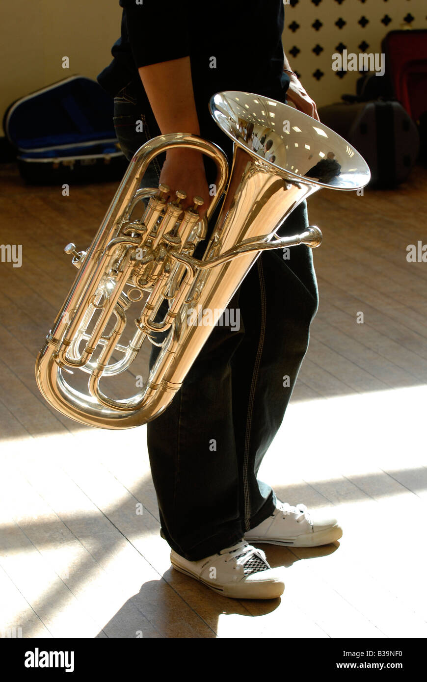 Musicista attraversando Soleggiato monolocale piano portante una tuba Foto Stock