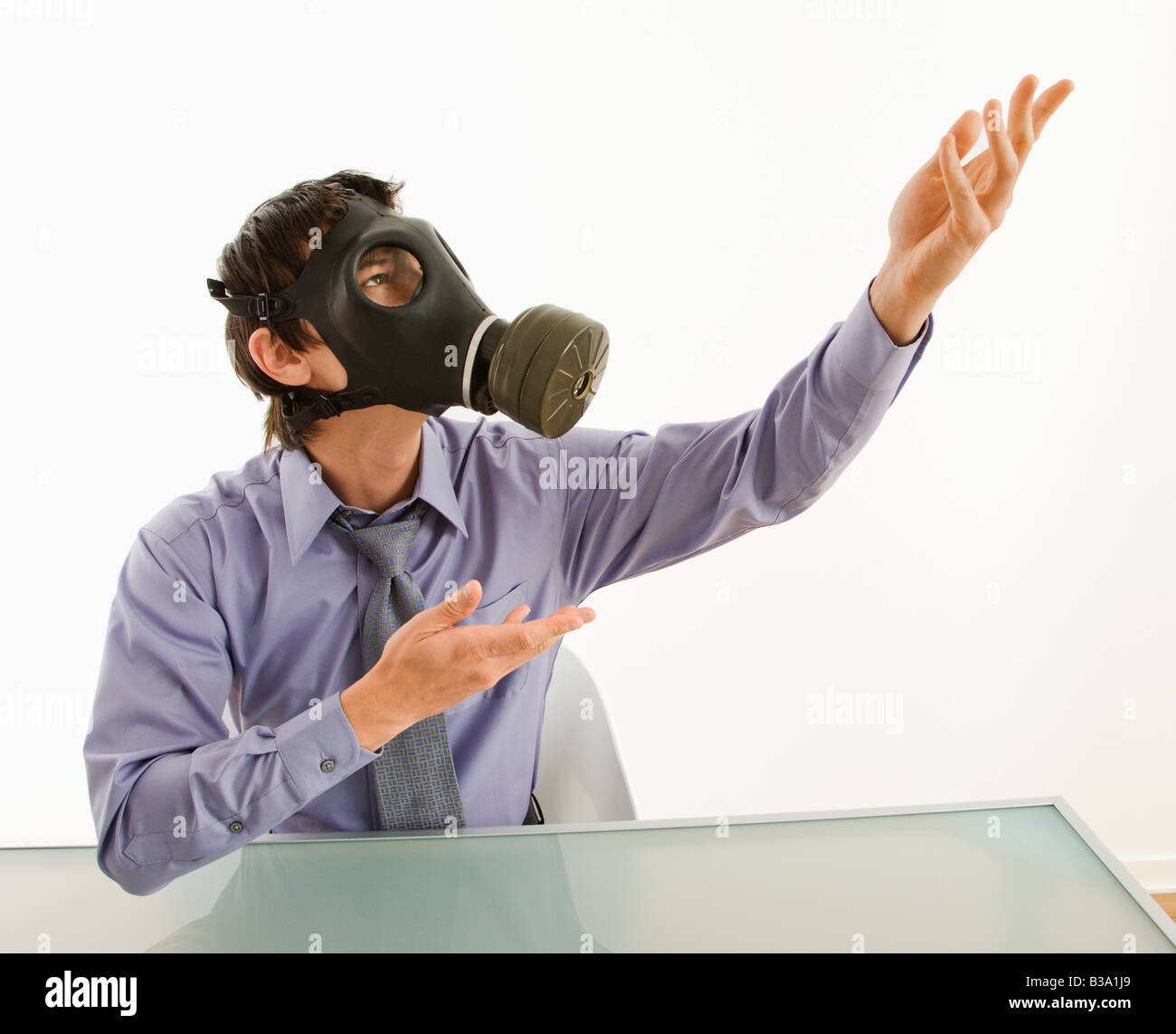 Imprenditore seduto in camera bianca indossando maschera a gas gesticolando a persona sconosciuta Foto Stock