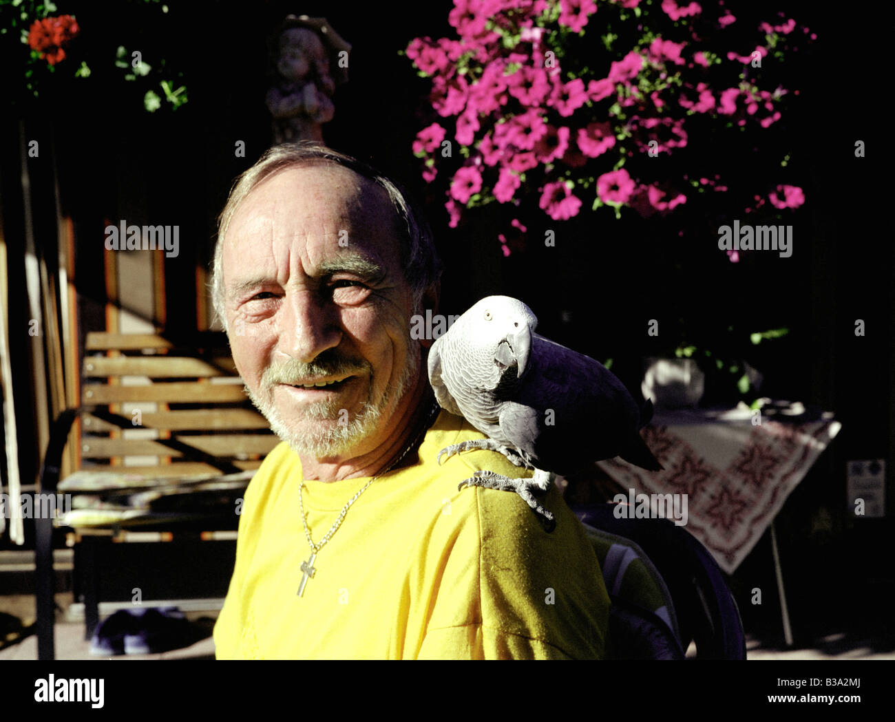 Uomo in maglietta gialla con il pappagallo sulla spalla Foto Stock