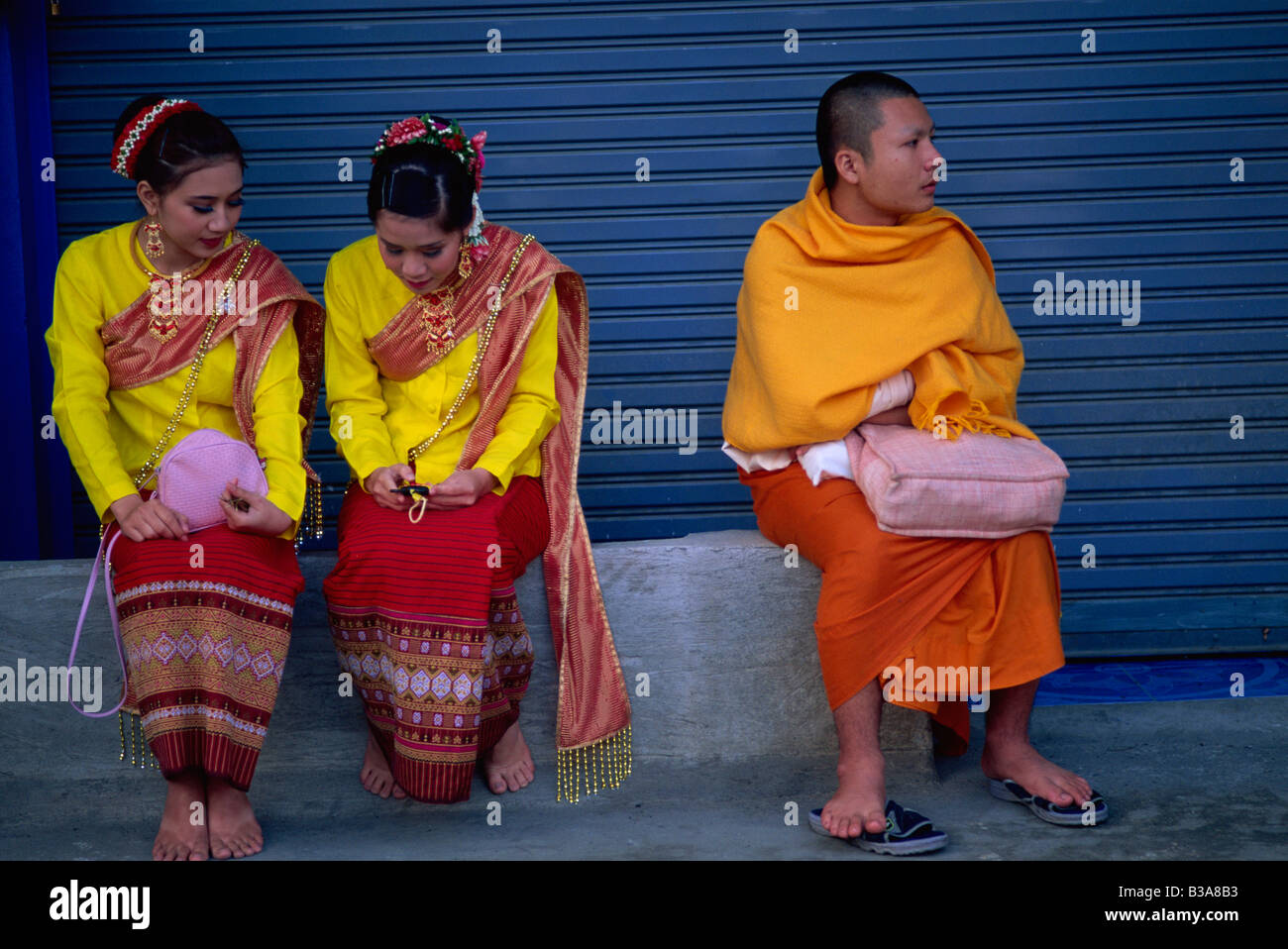 Thailandia Chiang Mai, due ragazze in costume tradizionale e un monaco Foto Stock