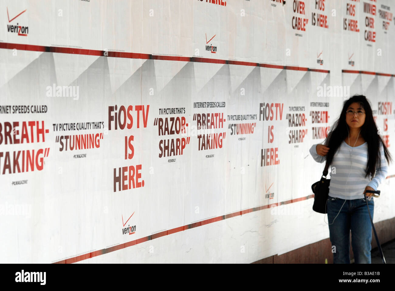 Una donna cammina passato poster pubblicità Verizon FiOS service in New York Foto Stock