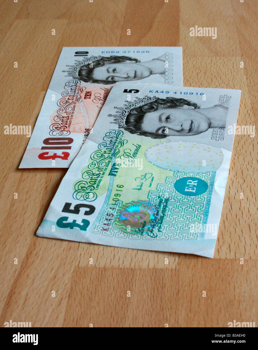 Un £5 e £10 nota ( Sterling ) disposti su una tavola di faggio. Foto Stock