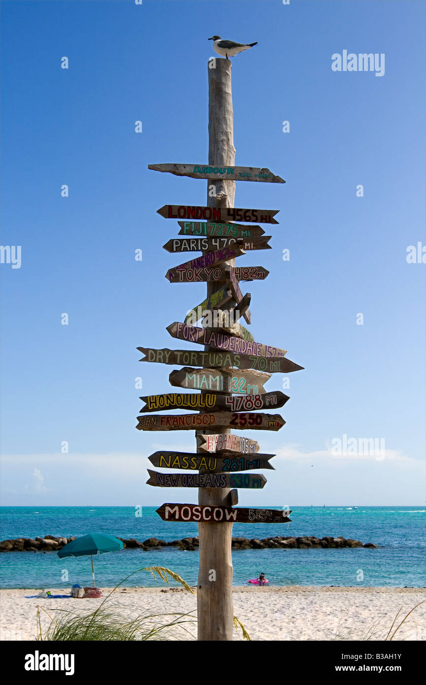 Un segno di distanza con un uccello sulla parte superiore su una spiaggia di Key West, Florida, Stati Uniti d'America Foto Stock
