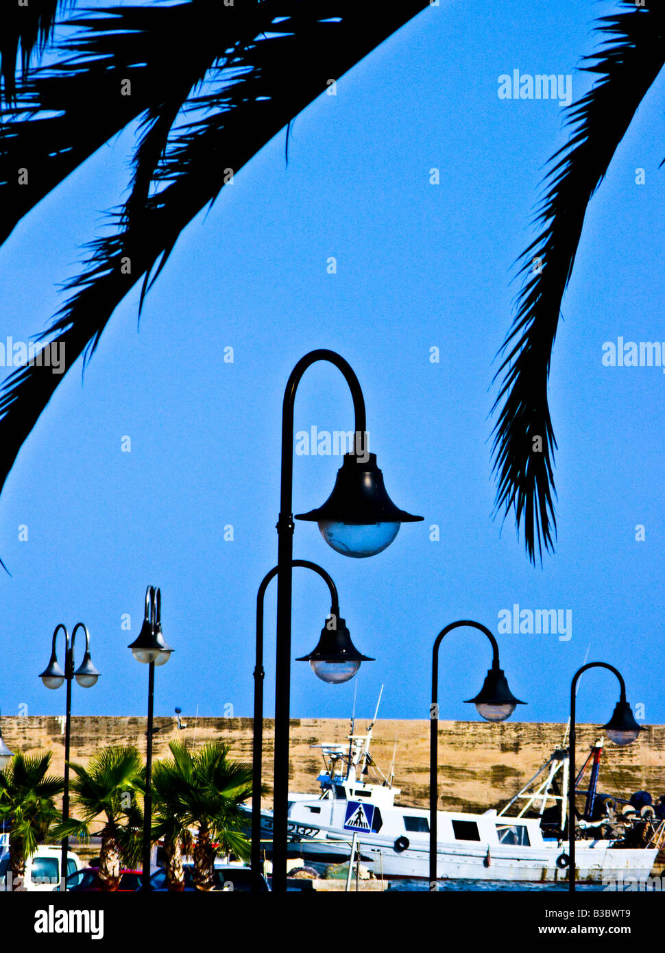 Lampioni, palme e fisherman barca sotto un cielo blu Foto Stock