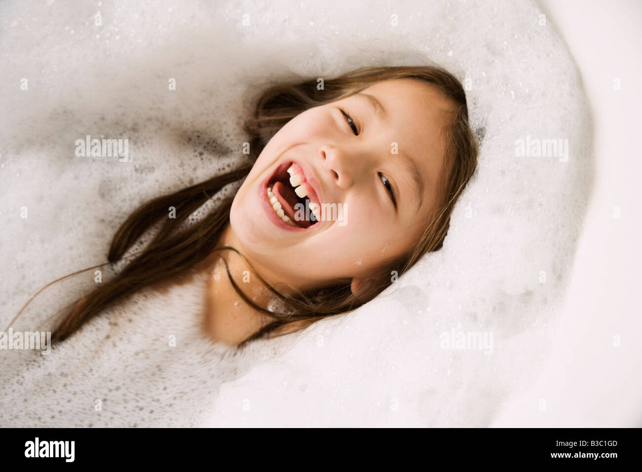 Ragazza asiatica ridere in bagno di bolle Foto Stock