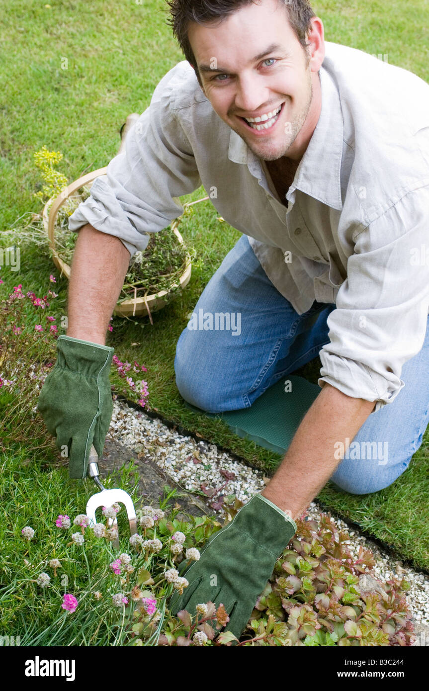 Un uomo piantare fiori in un giardino Foto Stock