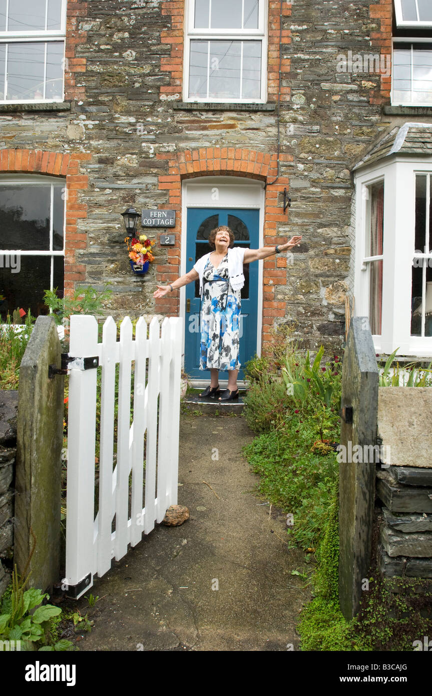 Felice lady titolare di pensione o di rendita di fronte alla sua casa cottage. Foto Stock