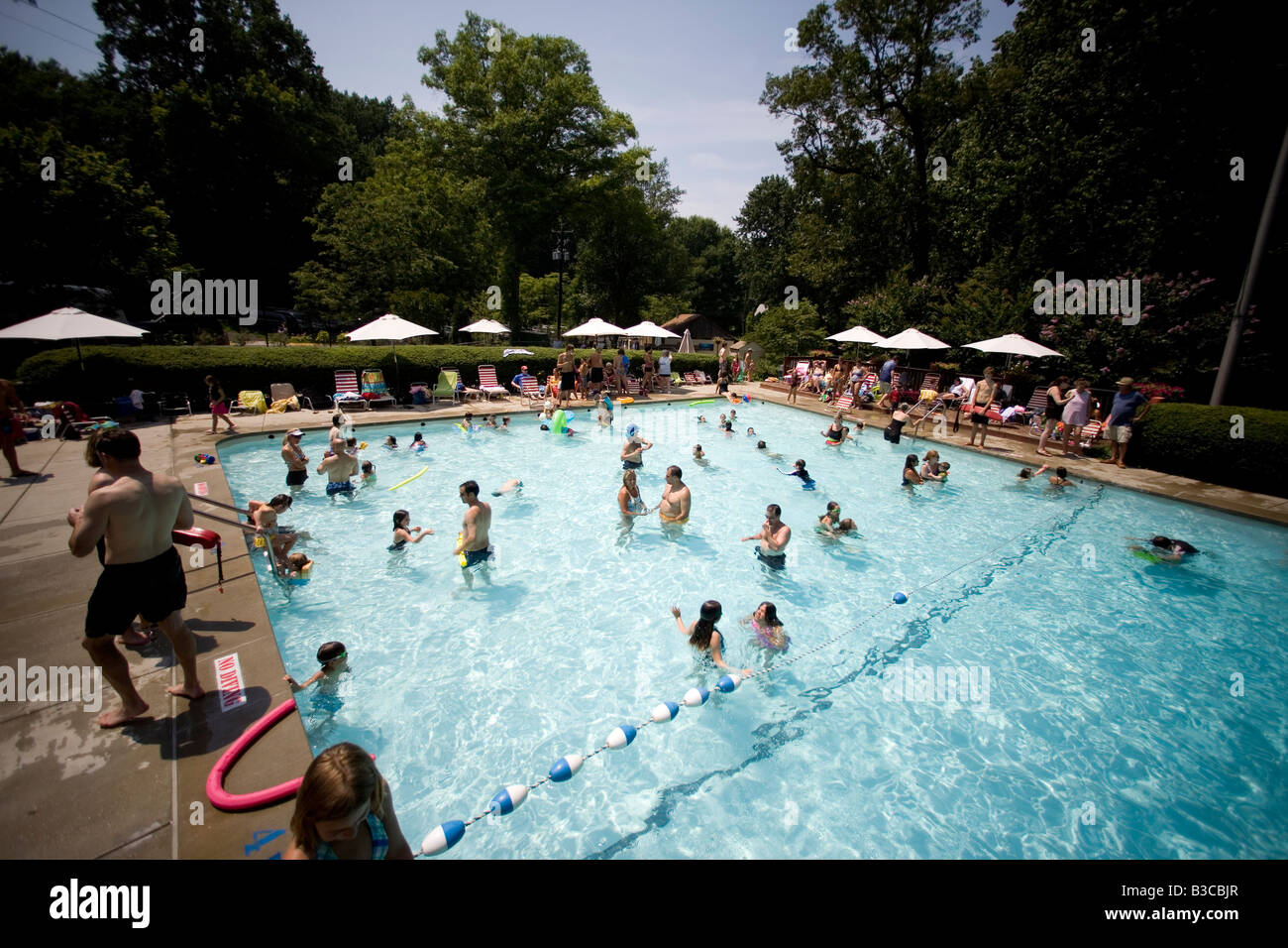 Le famiglie e i nuotatori godere di una piscina locale durante una calda giornata d'estate. Foto Stock