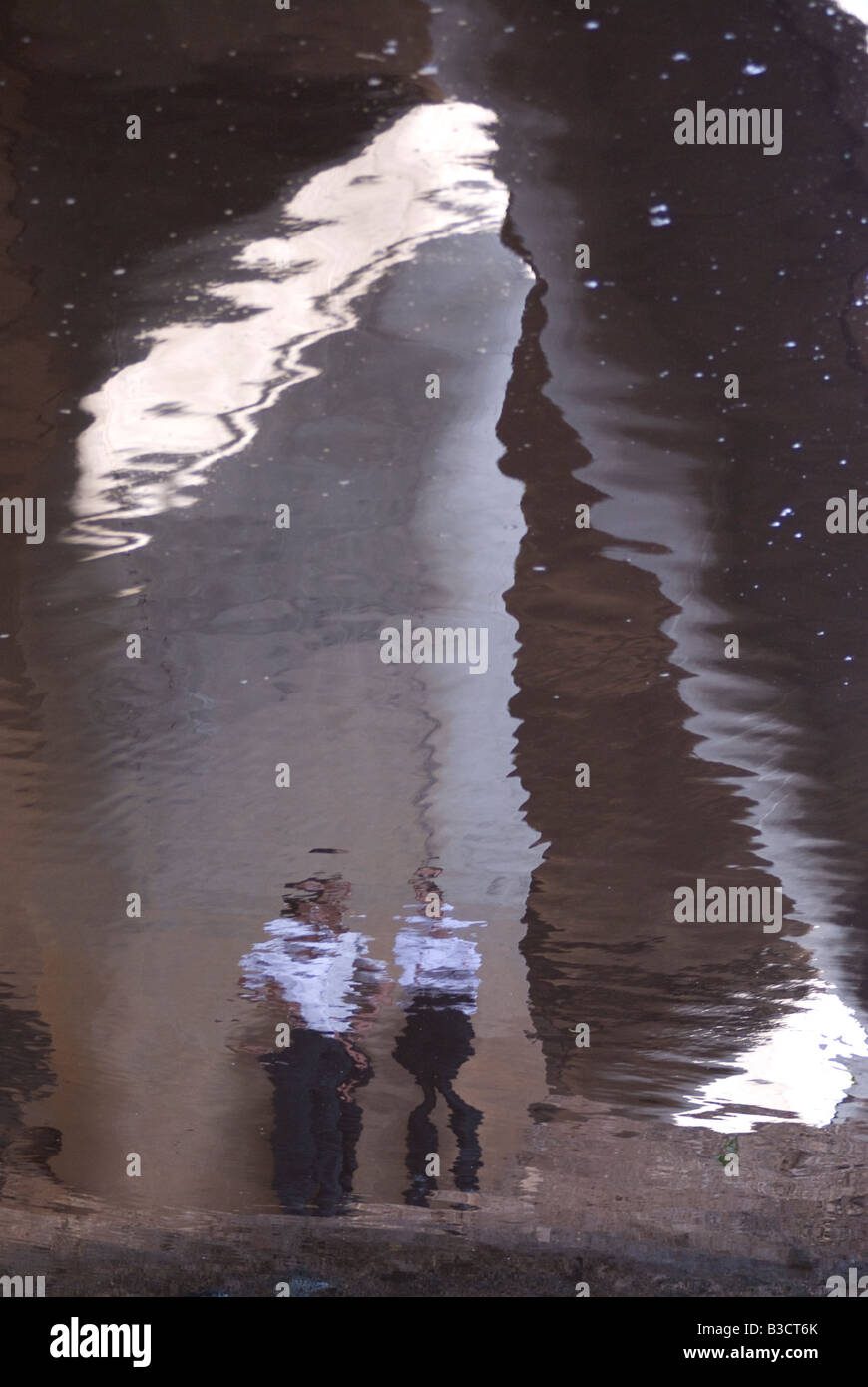 La riflessione in acqua di persone in piedi sotto un ponte sul fiume yarkon che fluisce attraverso il Gush Dan nel mare mediterraneo di tel aviv, Israele Foto Stock