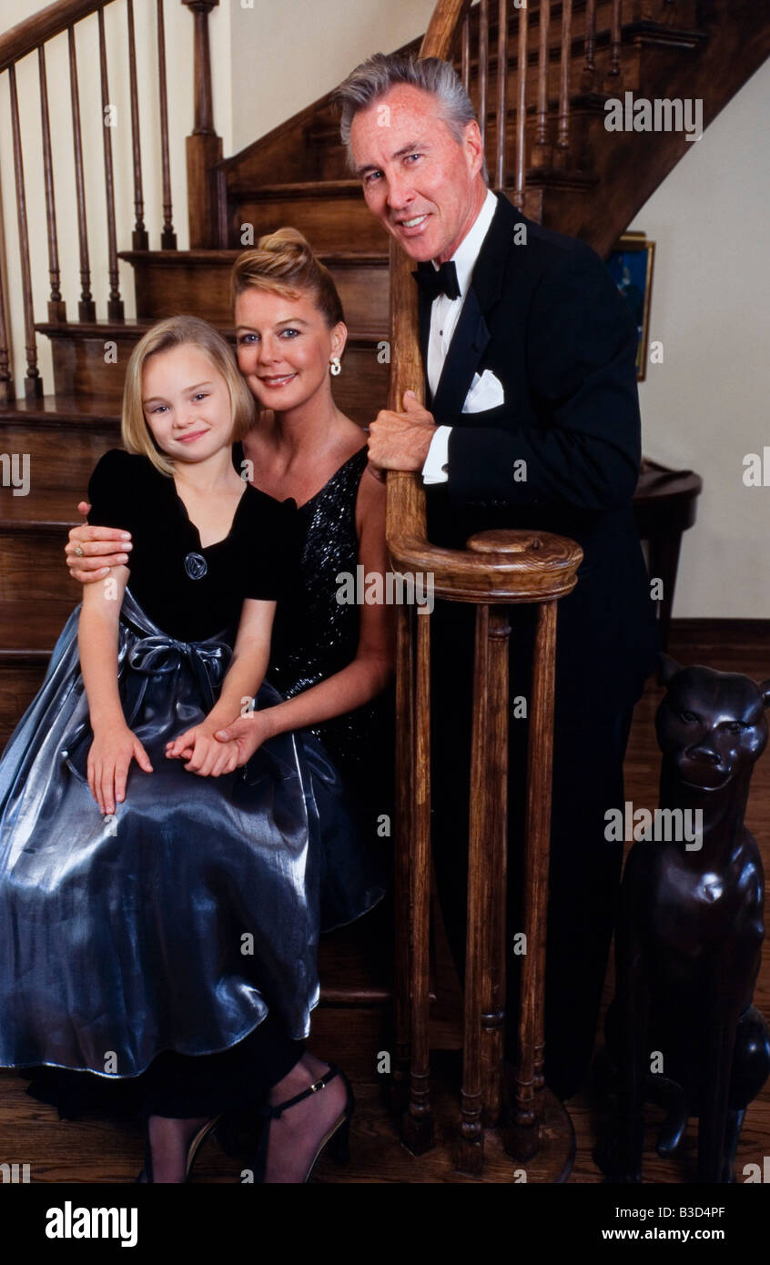Famiglia vestito elegante per l'occasione, abbracciando insieme, felice e orgoglioso. Foto Stock