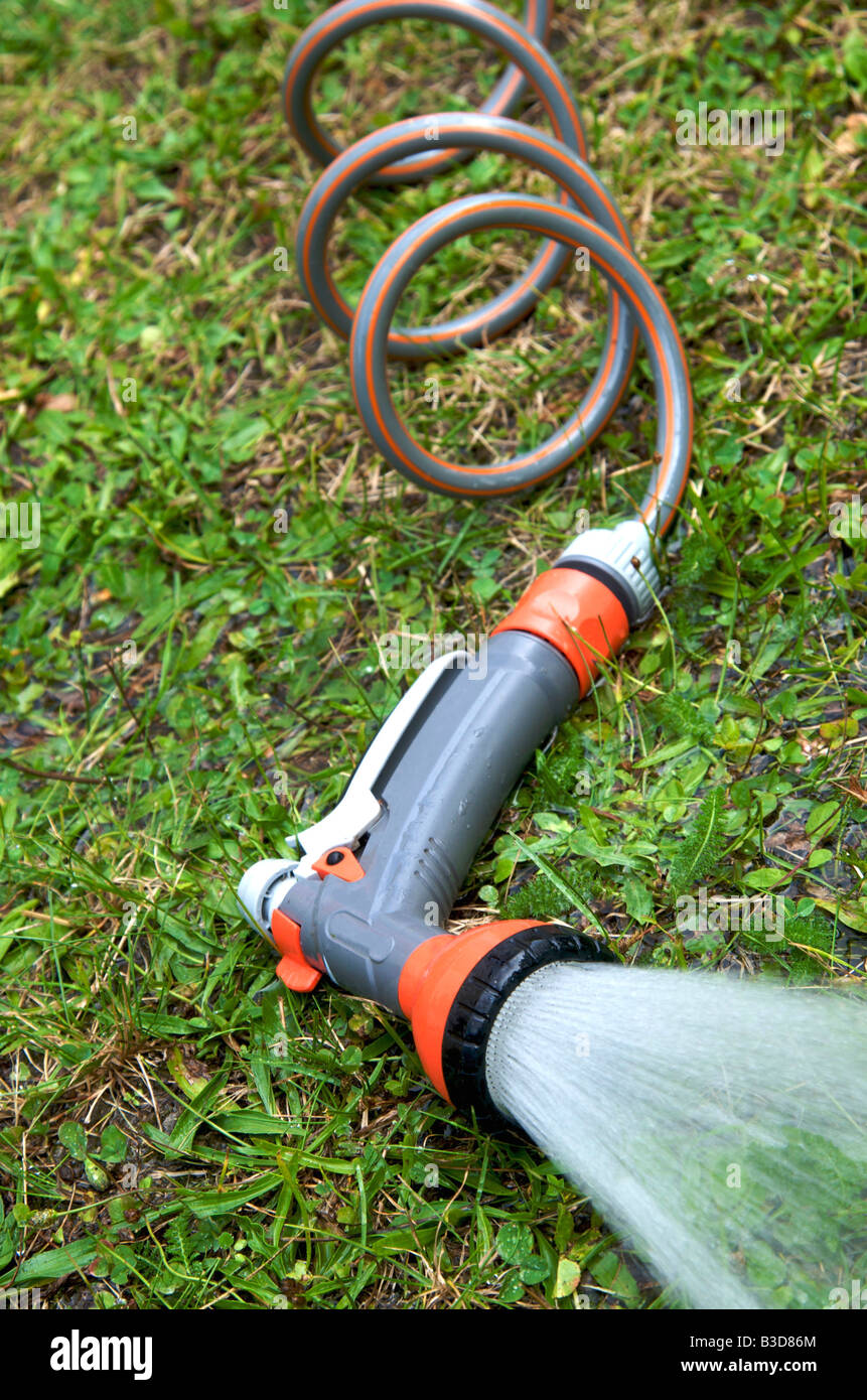 Irrigatore per giardini che spruzza acqua in un giardino lussureggiante durante una giornata di sole Foto Stock Irrigatore per giardini che spruzza acqua in un giardino lussureggiante durante una giornata di sole Foto Stock