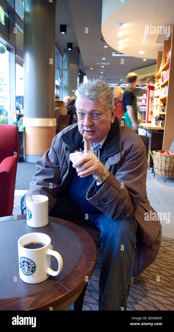 Alimenti e bevande, uomo si siede a un tavolo in una caffetteria e due tazze di caffè stand sul tavolo Foto Stock