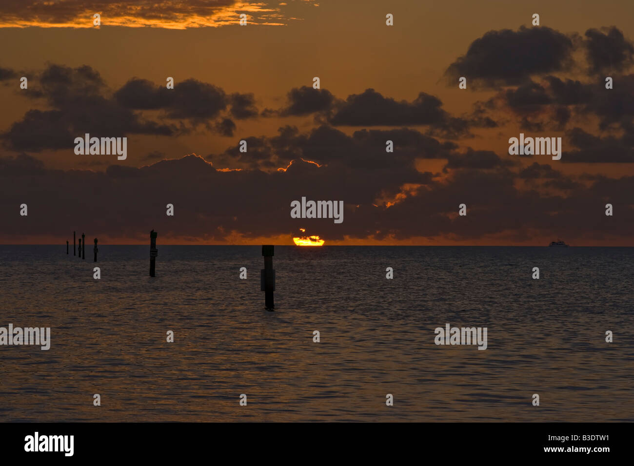 Round orange il sorgere del sole al di fuori del mare in nuvole basse, orange red sky e riflessi arancione in alto nuvole Key Largo, Florida, Stati Uniti d'America Foto Stock