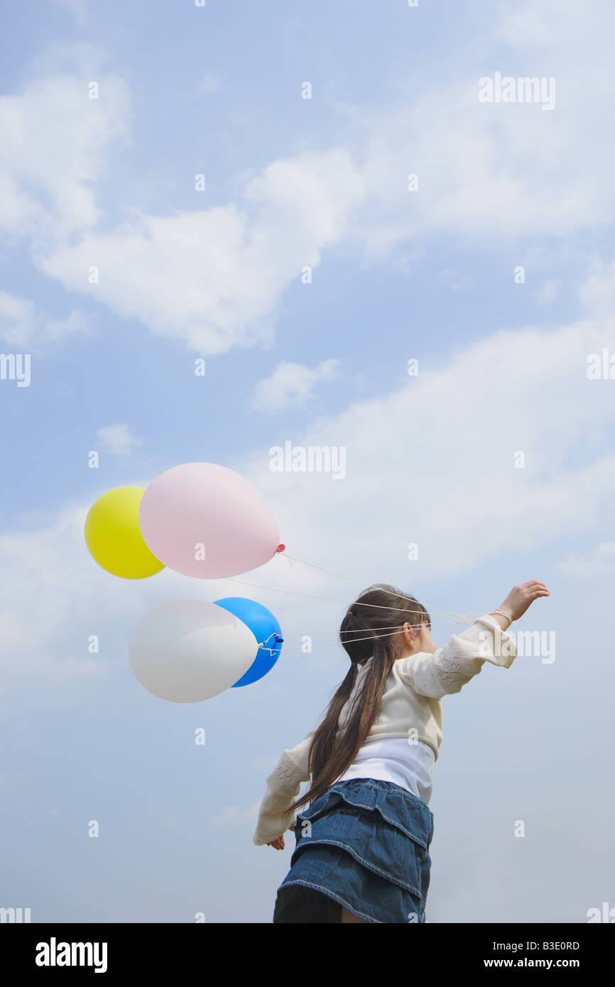 Ragazza con palloncini contro il cielo nuvoloso Foto Stock