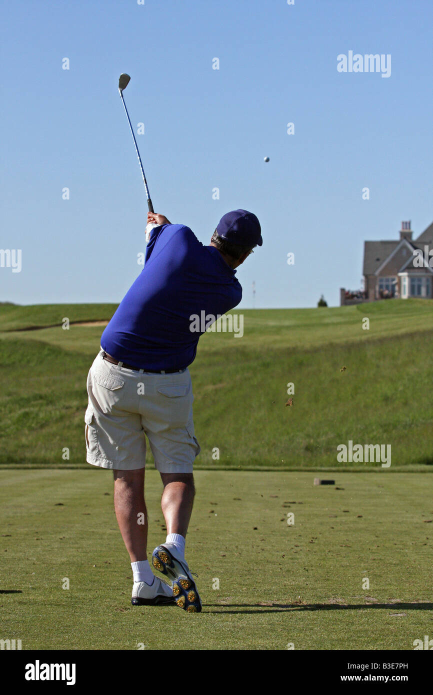 Giocatore di golf con un grande swing del golf attraverso il seguente dopo aver colpito la sua tee-shot dalla scatola a t su una salita con una par 3. Foto Stock