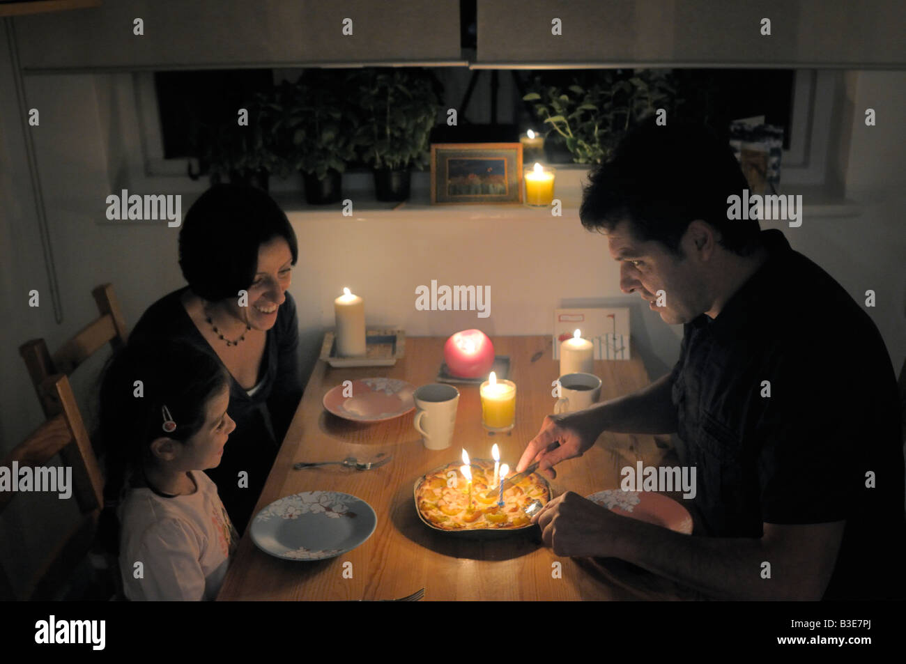 La famiglia intorno alla tavola per festeggiare un compleanno a lume di candela Foto Stock