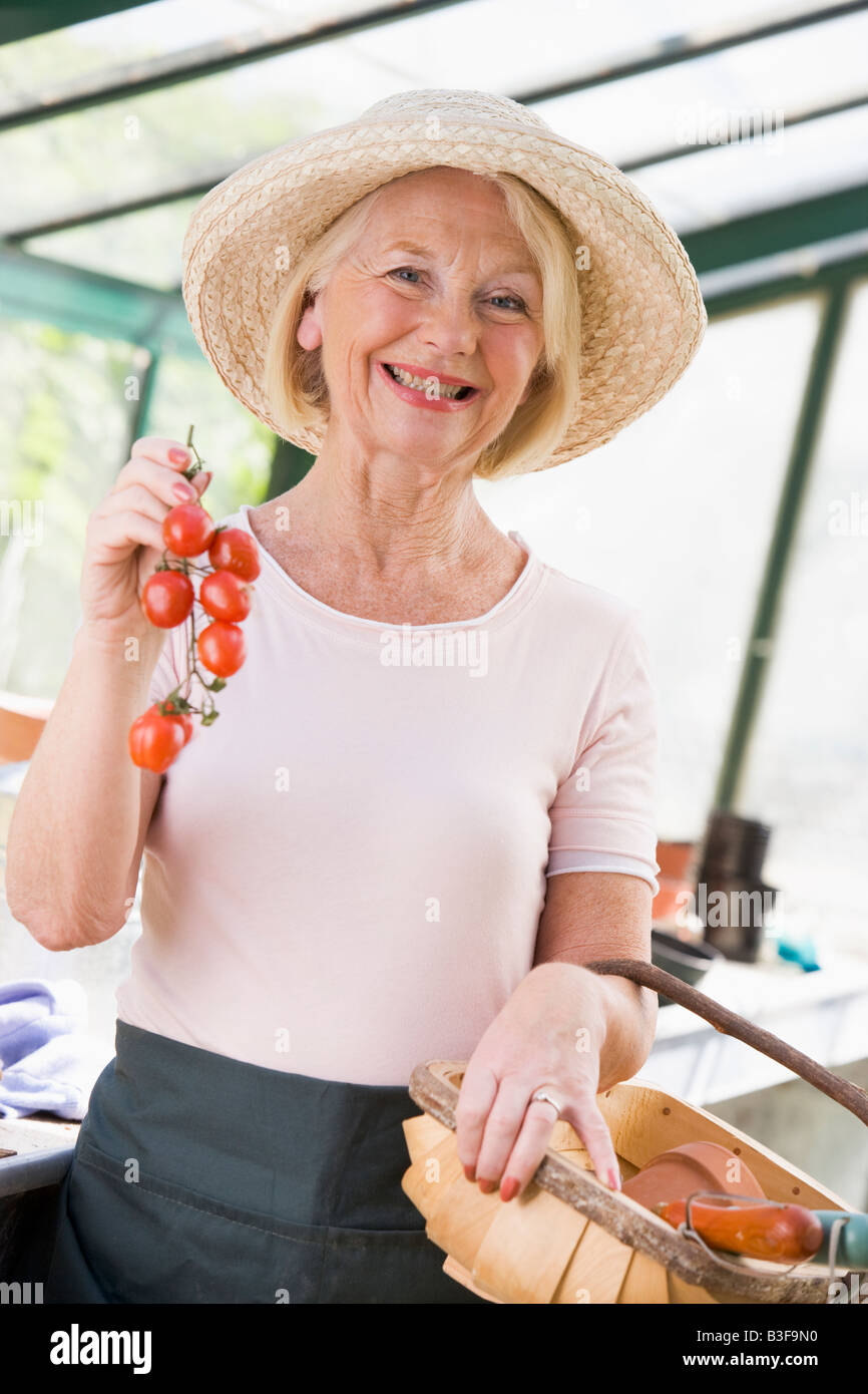 Donna in azienda serra pomodori ciliegia sorridente Foto Stock