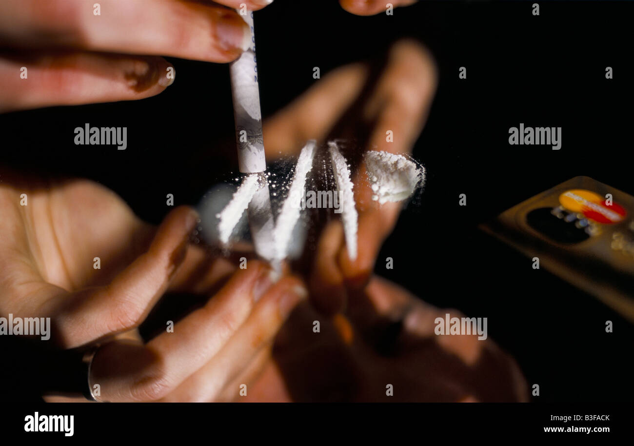 Una giovane donna sbuffare una linea di cocaina fuori uno specchio attraverso un arrotolato nota banca.poste dal modello. Foto Stock