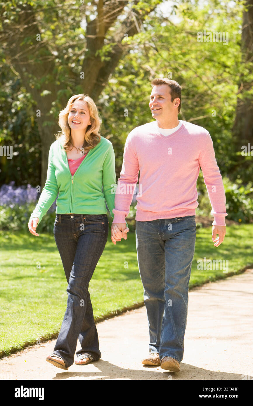 Giovane camminando sul sentiero tenendo le mani sorridente Foto Stock