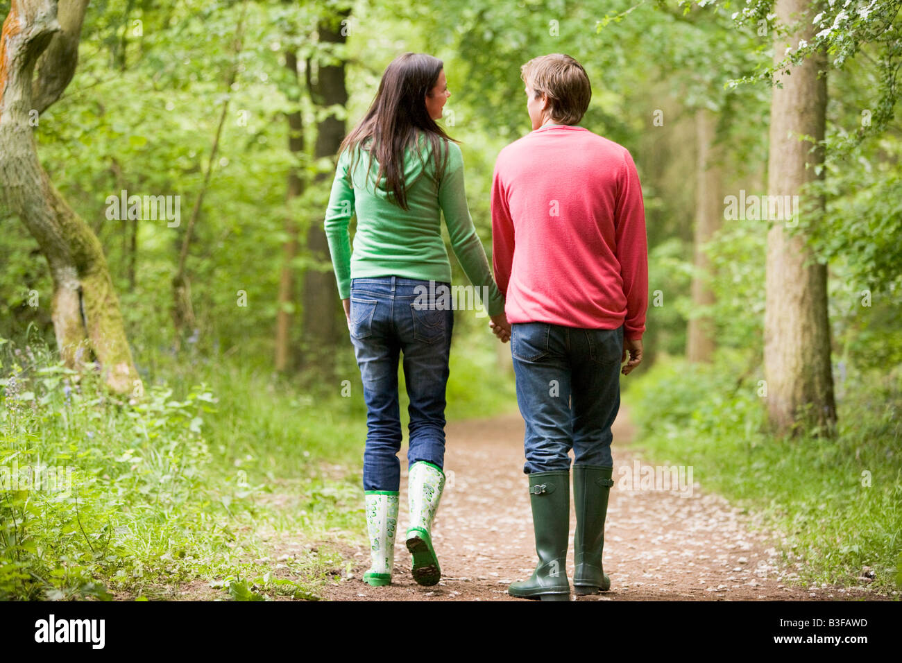 Giovane camminando sul sentiero tenendo le mani Foto Stock