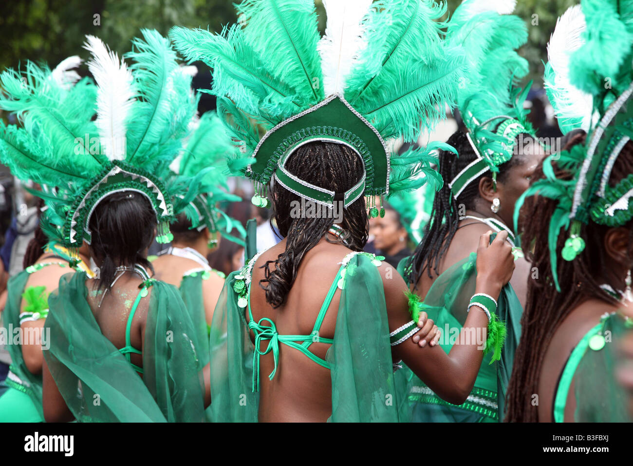 Ballerini in costumi di piuma verde al Carnevale di Notting Hill, Londra, - vibrante festa di strada multiculturale Foto Stock