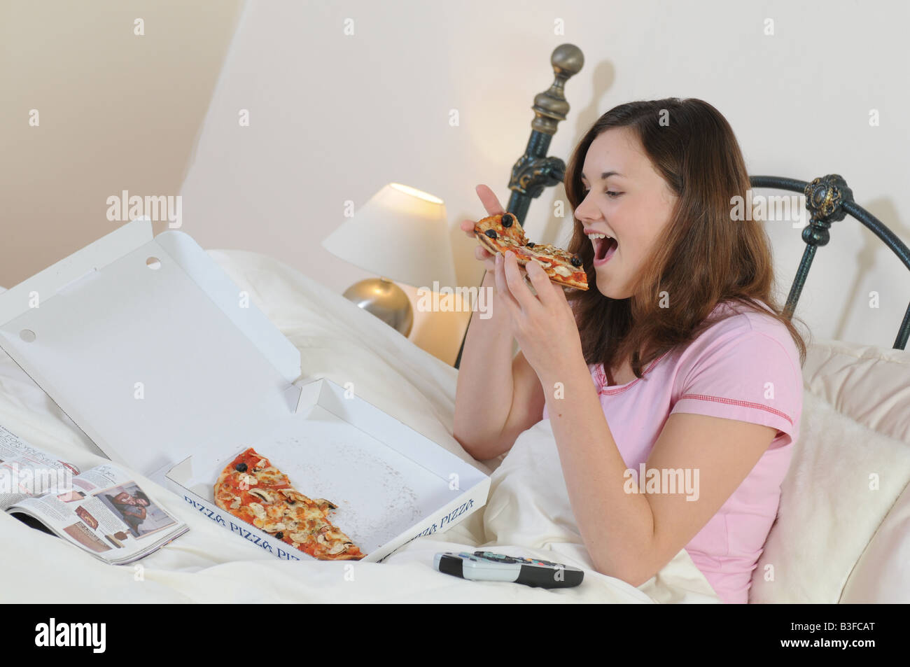 Una ragazza nel letto junkfood mangiare guardando la televisione Foto Stock