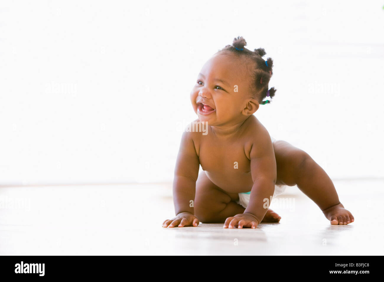 Il bambino gattona sorridente in interni Foto Stock