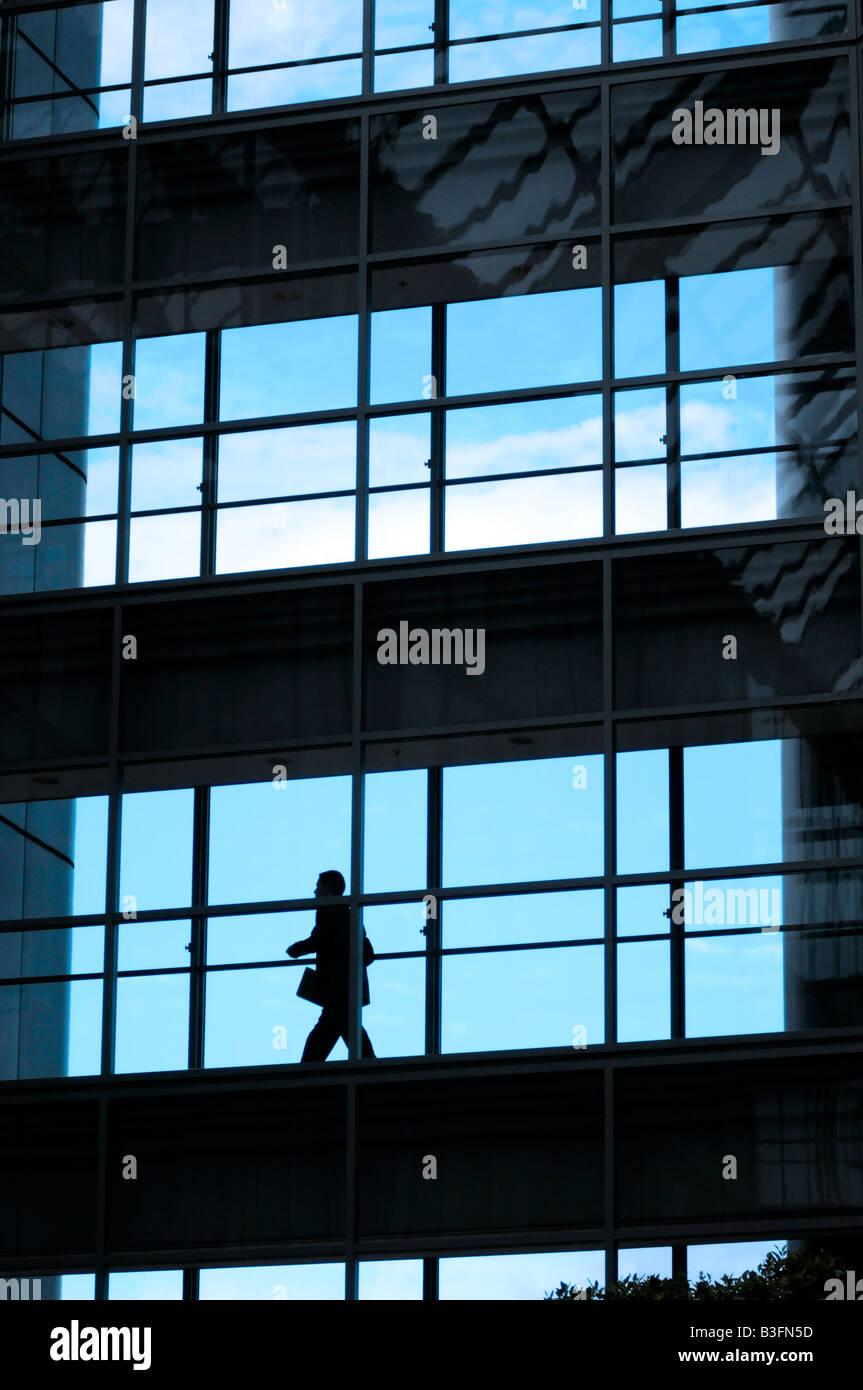 Royalty free fotografia di business man walking in vetro ufficio edificio stagliano contro il cielo di sera. Foto Stock