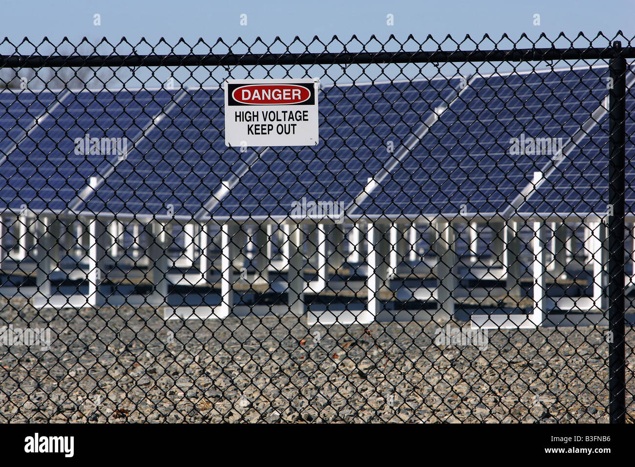 Un segno avverte di alta tensione al di fuori di un pannello solare di generazione di elettricità in array Brockton Massachusetts Foto Stock