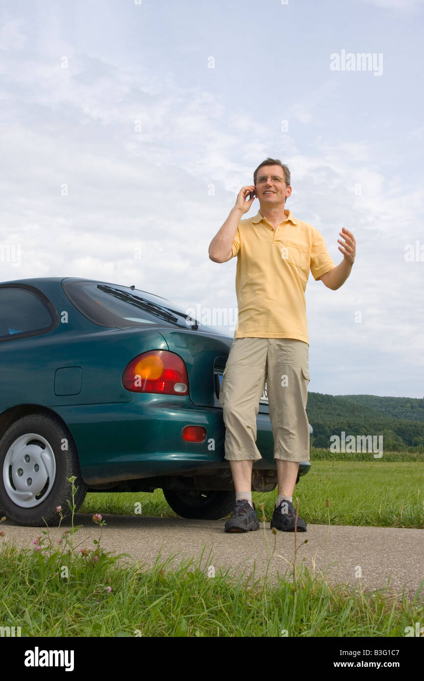 L'uomo parlando al cellulare accanto alla sua automobile Foto Stock