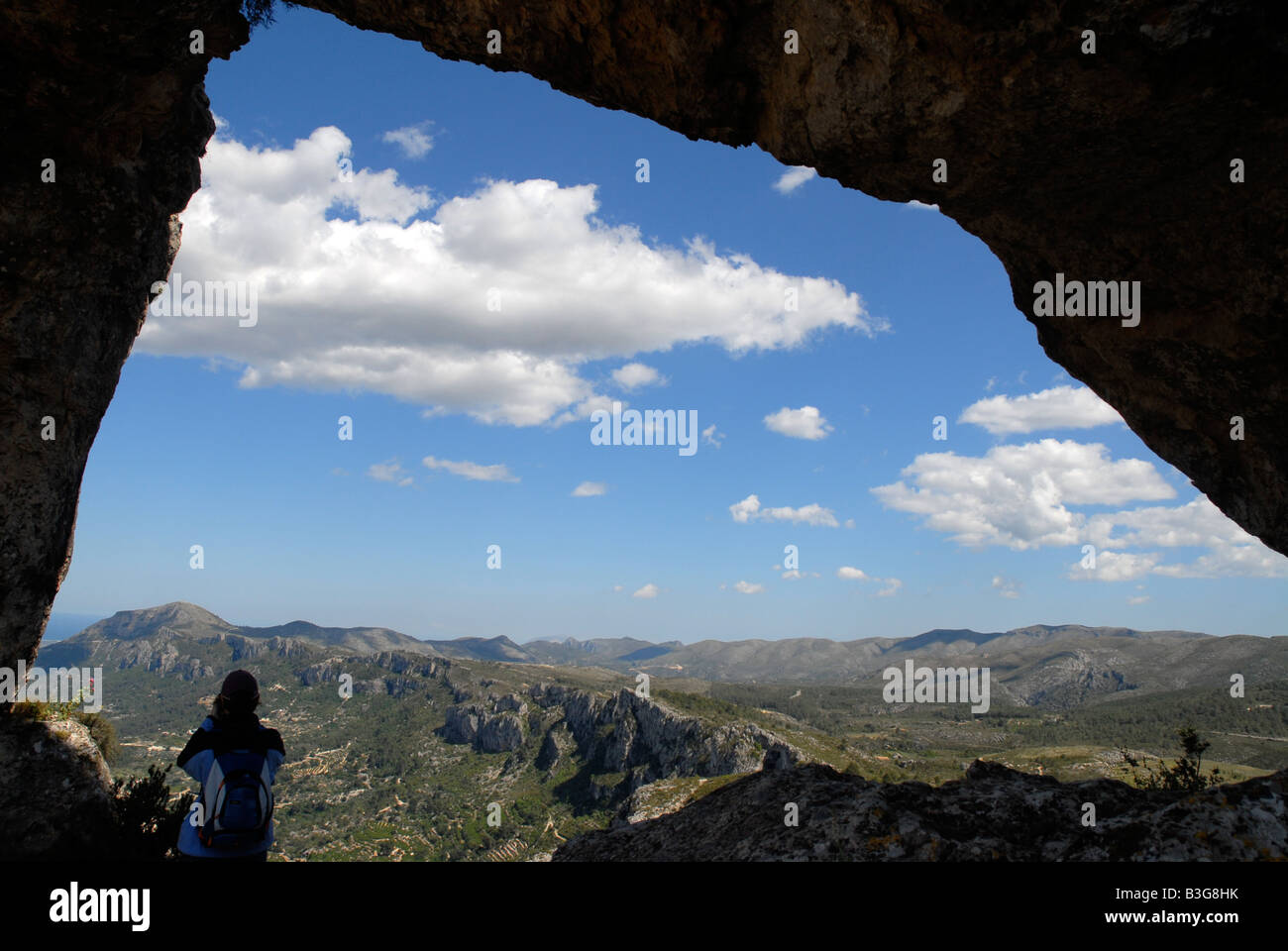 Donna escursionista presso la roccia Forada Arch, Sierra de la Forada, Provincia di Alicante, Comunidad Valenciana, Spagna Foto Stock