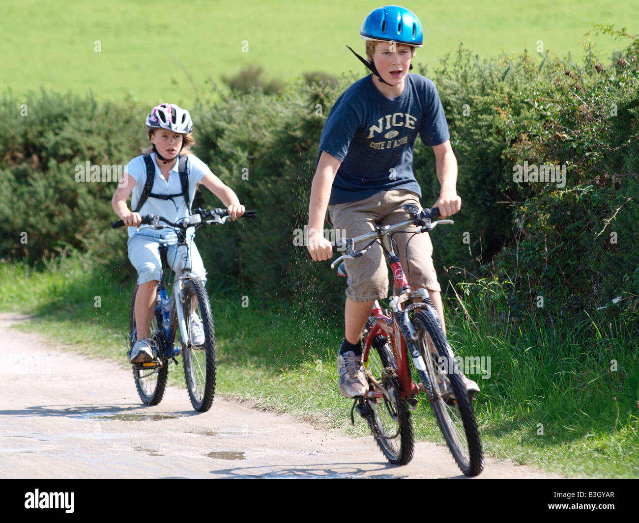 Un ragazzo e una ragazza su biciclette a cavallo lungo il sentiero del cammello, Padstow, Cornwall, Regno Unito Foto Stock